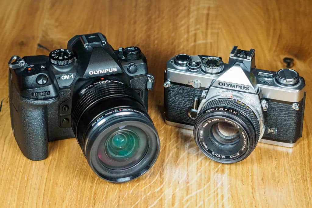 one large and one small olympus camera placed on a surface