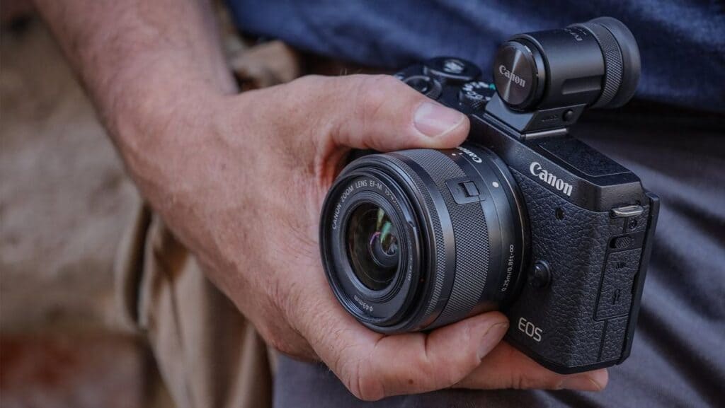 zoomed in view of a male hand carrying canon EOS M mark II