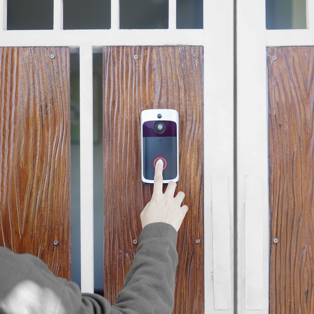 Close Up Of Hand Ringing Front Doorbell Equipped With Security